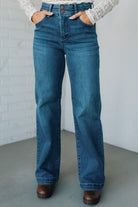 Person wearing blue jeans with a plain background