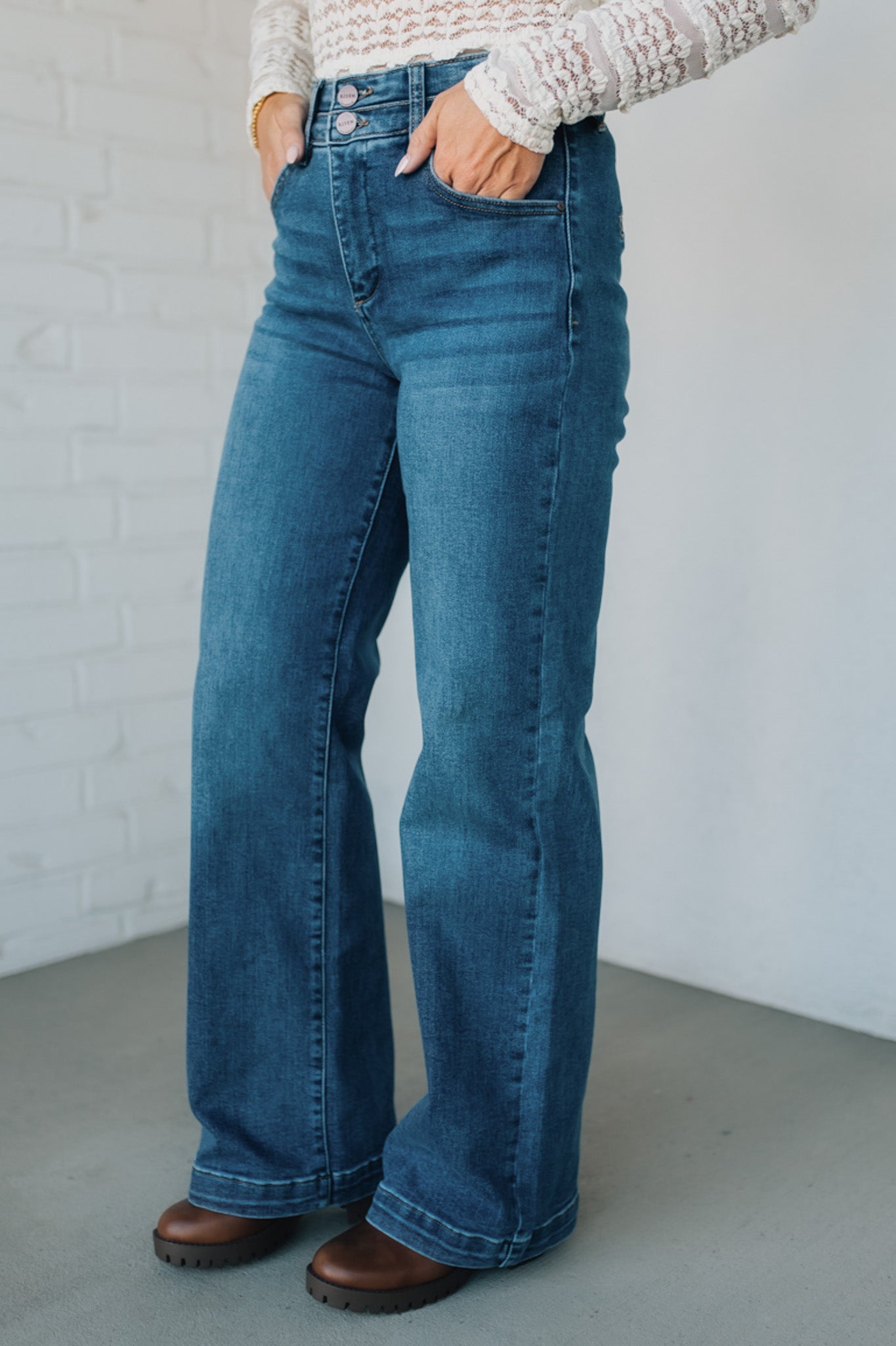 Person wearing blue jeans and a white textured sweater against a plain background