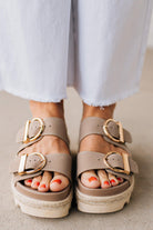 TAUPE PLATFORM SANDAL WITH TWO STRAPS FEATURING A LARGE GOLD BUCKLE ON EACH.