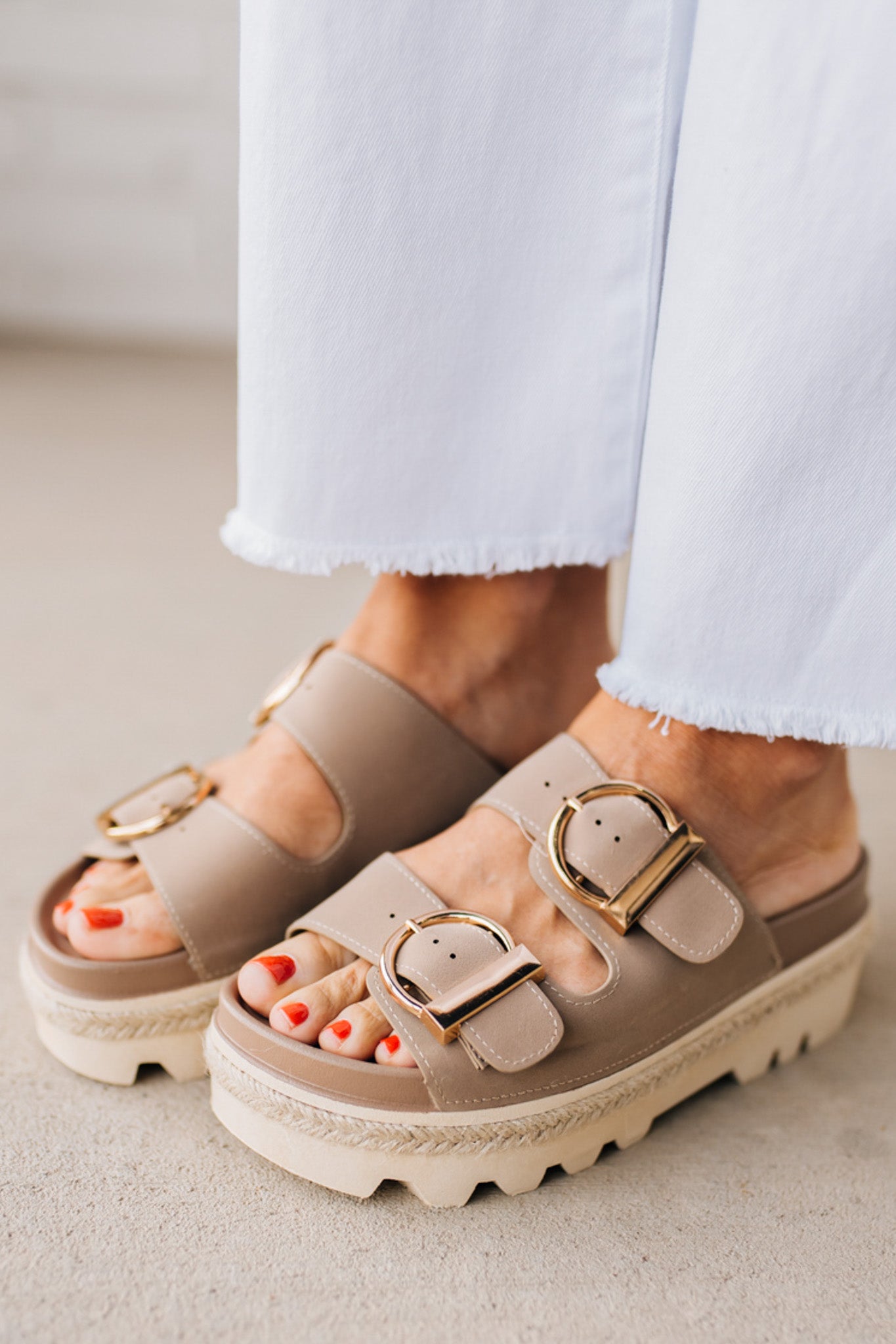 TAUPE PLATFORM SANDAL WITH TWO STRAPS FEATURING A LARGE GOLD BUCKLE ON EACH.