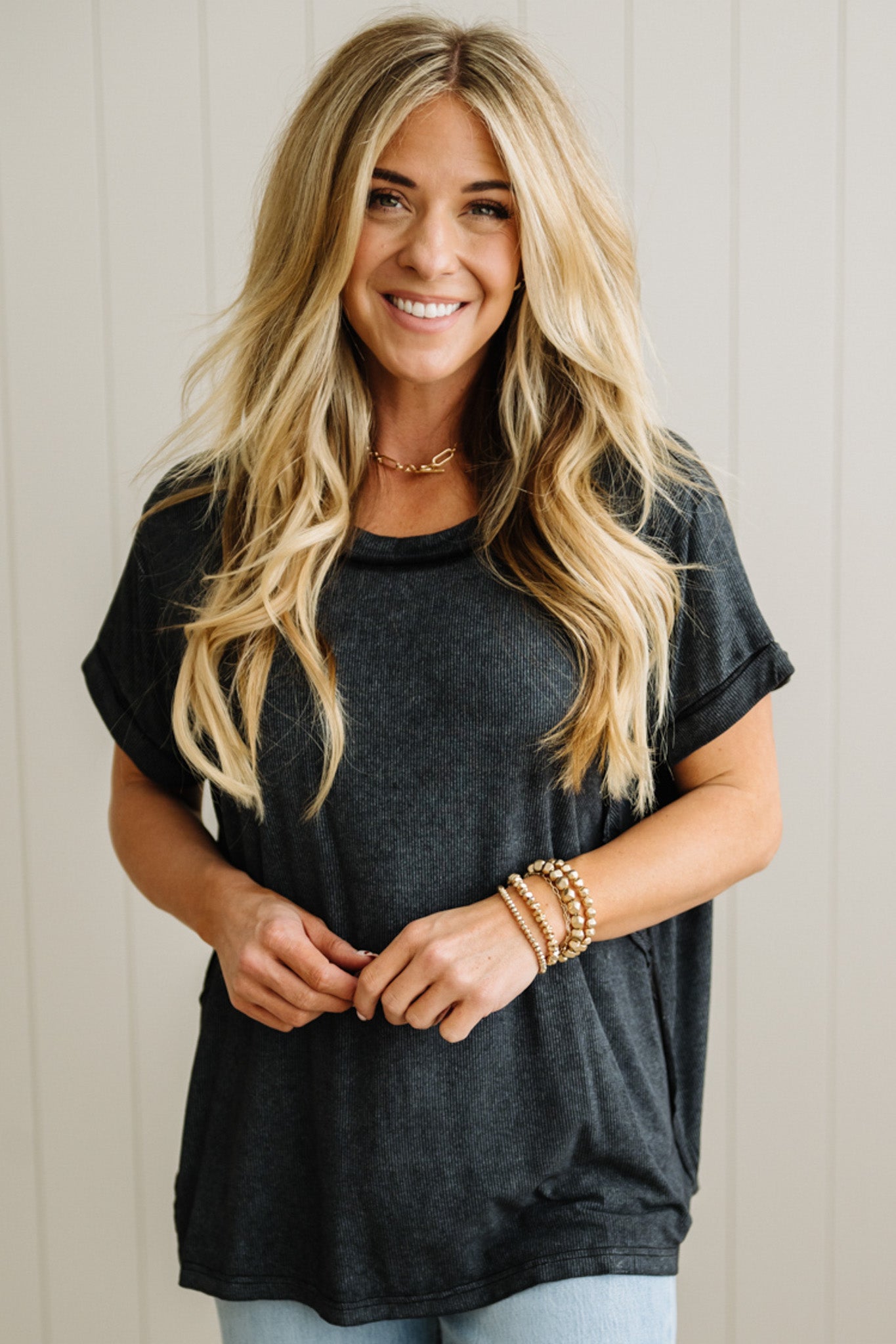 Woman wearing a black t-shirt and blue jeans with a neutral background