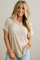 Woman wearing a beige t-shirt and light blue jeans against a plain background