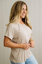 Woman wearing a beige top and blue jeans against a neutral background