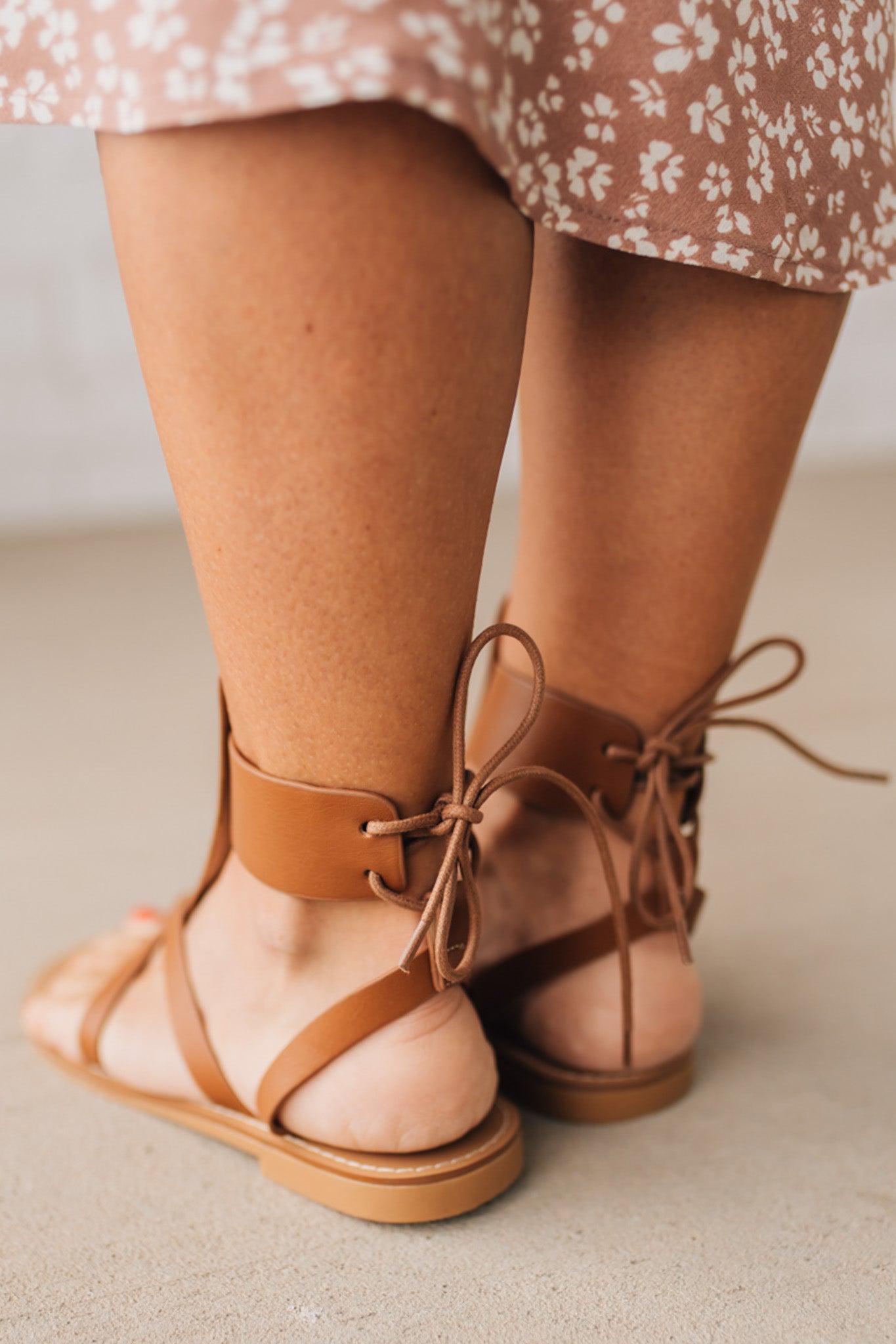 COGNAC BROWN FLAT FAUX LEATHER SANDALS WITH TIE BACK.