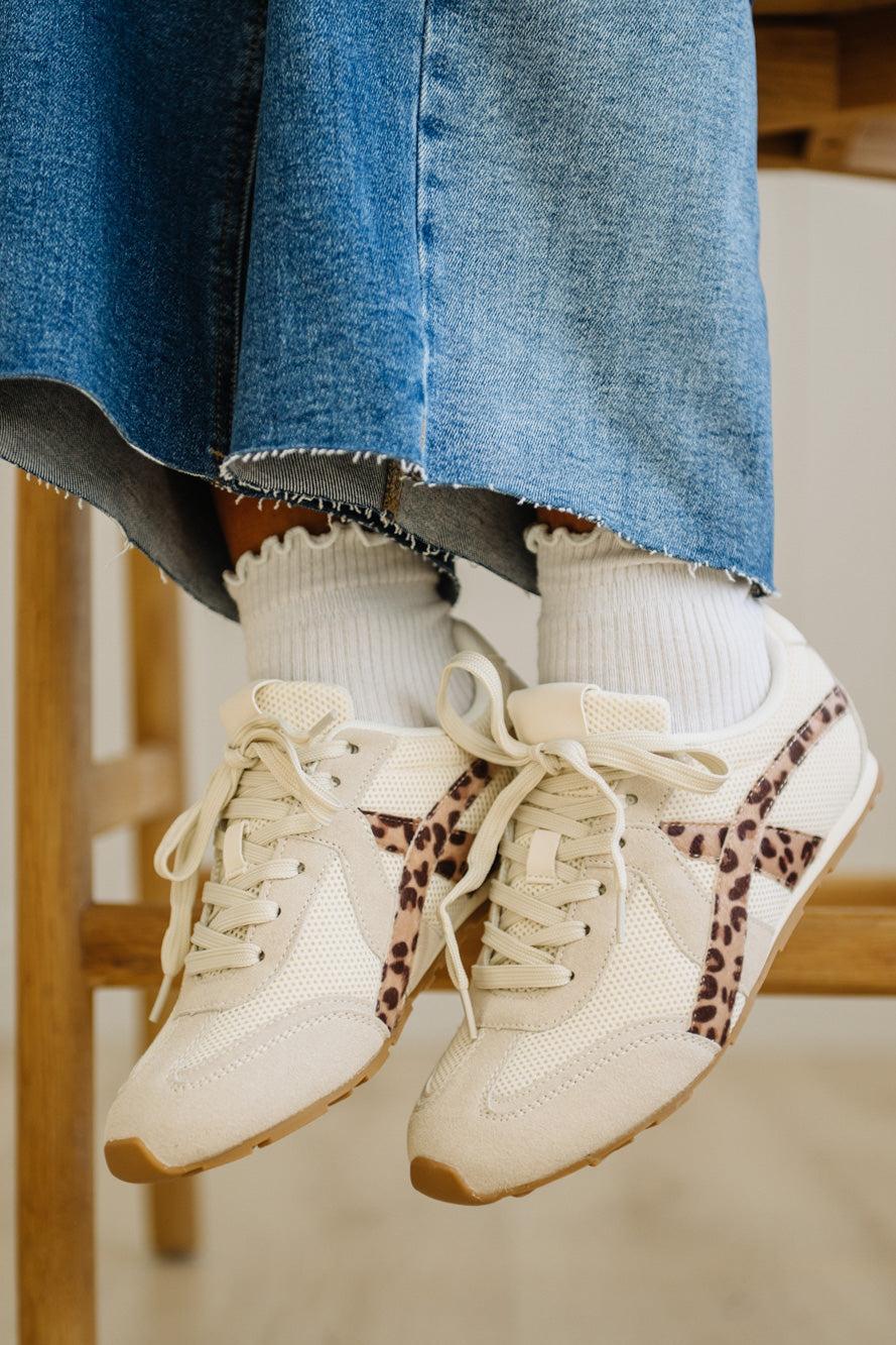 White sneakers with leopard print accents worn with ripped jeans and white socks.