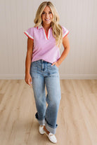 Woman wearing a pink and white striped shirt with blue jeans on a wooden floor.