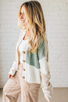 Woman wearing a patterned cardigan with a white brick wall background