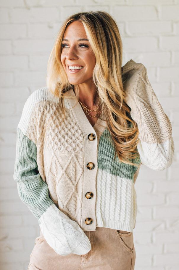 Woman wearing a patterned cardigan with a white brick wall background