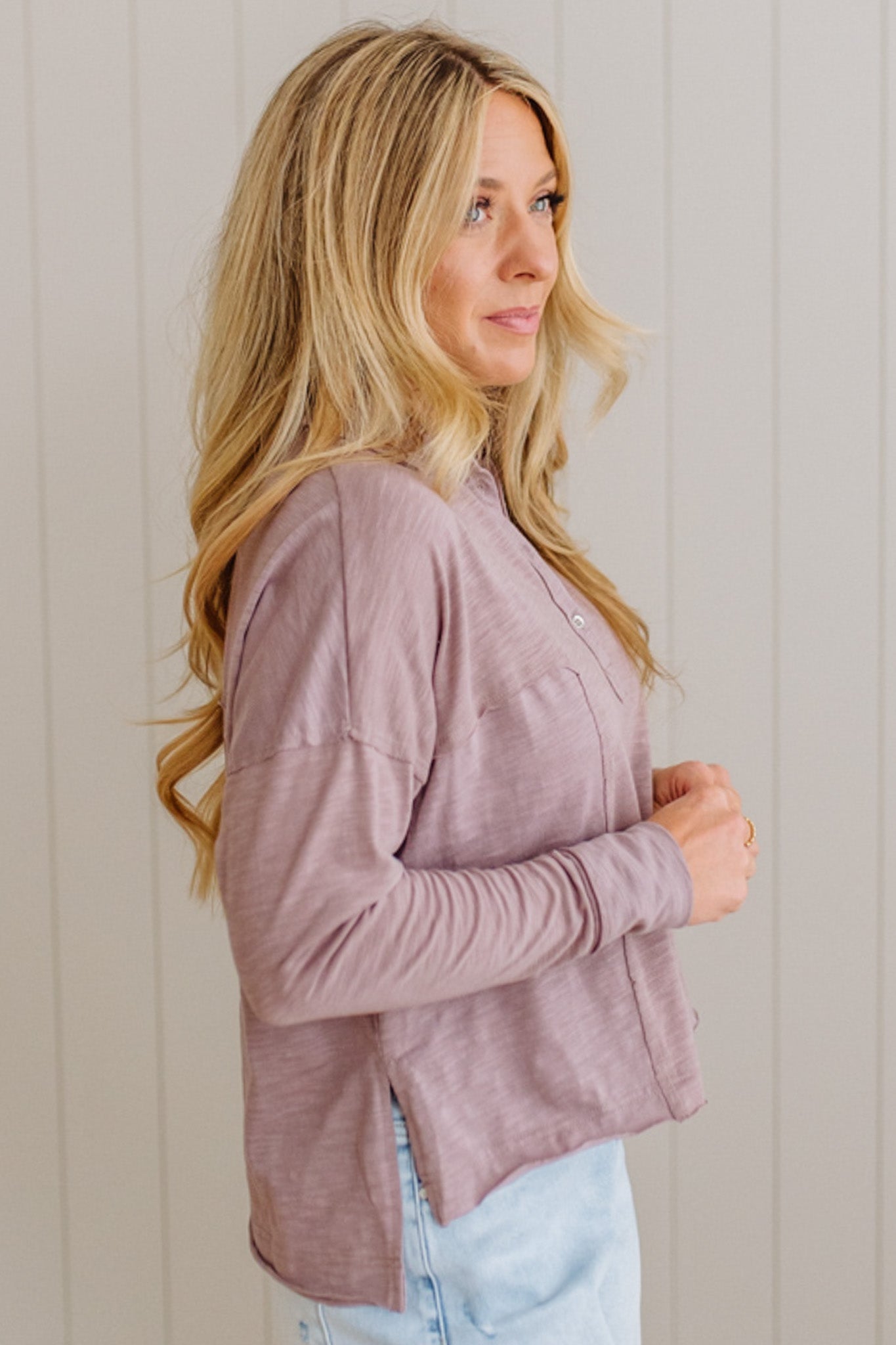 Woman wearing a mauve cardigan against a beige wall