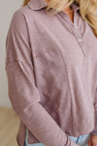 Close-up of a person wearing a mauve long-sleeve shirt with a neutral background