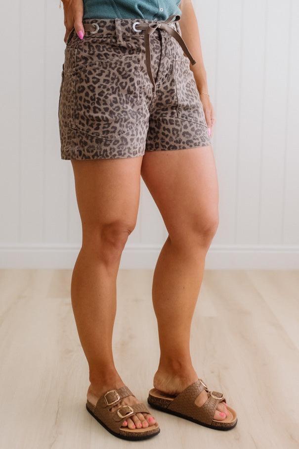Person wearing leopard print shorts on a plain background