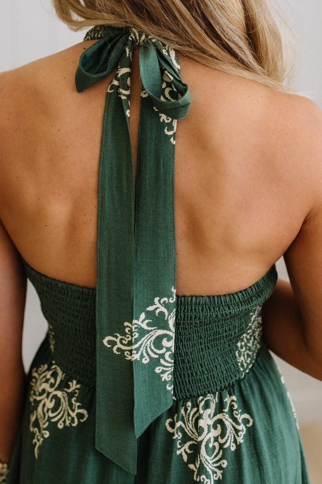 Green dress with intricate white patterns and a decorative tie at the back on a plain background