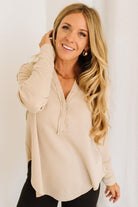 Woman wearing a beige long-sleeve top with a white background