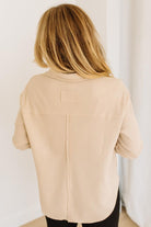 Person wearing a beige top with a plain background