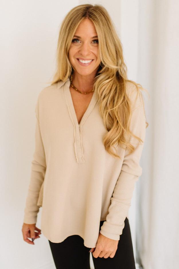 Woman wearing a beige long-sleeve top against a white background