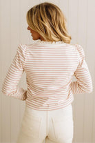 Person wearing a striped shirt and white pants against a neutral background