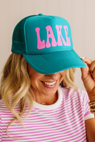 Person wearing a teal cap with 'LAKE' in pink on a neutral background
