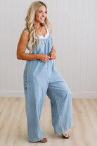 Woman wearing a light blue denim jumpsuit against a plain background