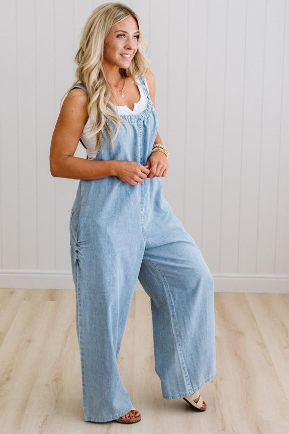 Woman wearing a light blue denim jumpsuit against a plain background