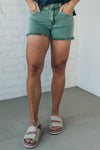 women wearing mid rise frayed shorts that have an olive green mineral wash finish