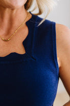 Navy blue sleeveless top worn by a person with a blurred background