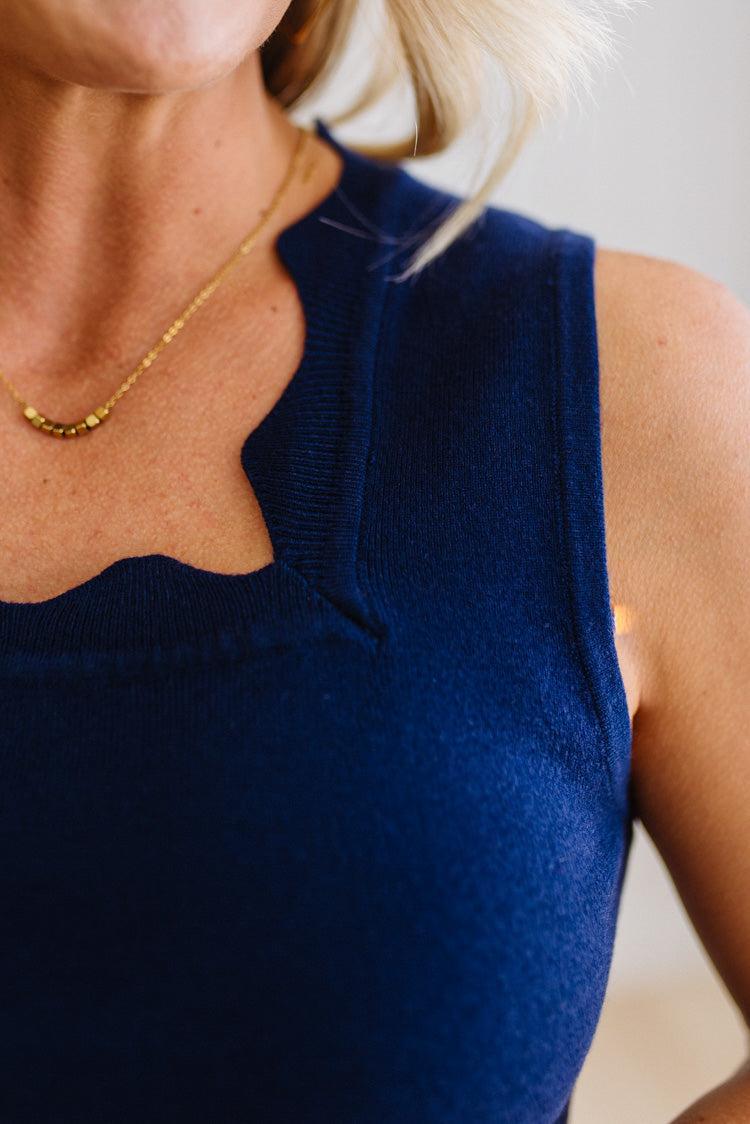 Navy blue sleeveless top worn by a person with a blurred background