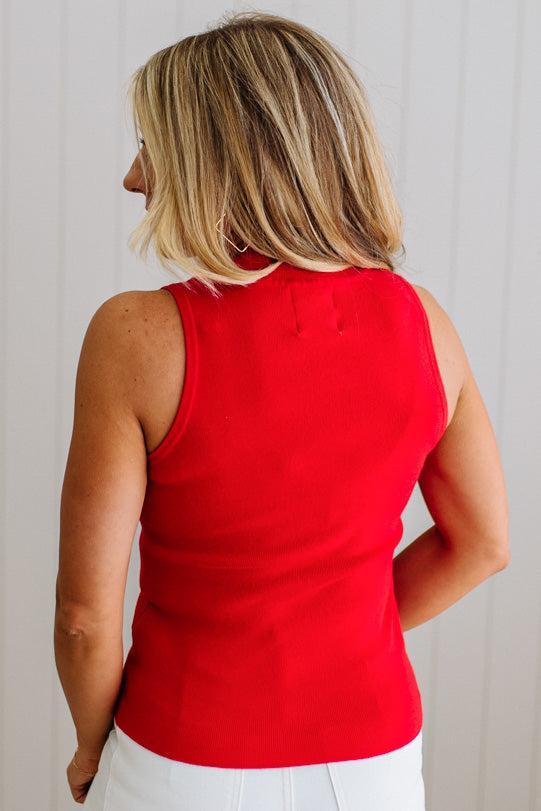 Person wearing a red sleeveless top against a plain background
