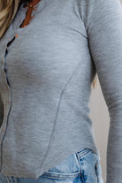Close-up of a person wearing a gray ribbed sweater and blue jeans against a neutral background