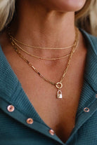 Close-up of a person wearing multiple gold necklaces with a green top.