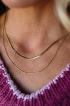 Close-up of a person wearing a gold necklace with a pink sweater.