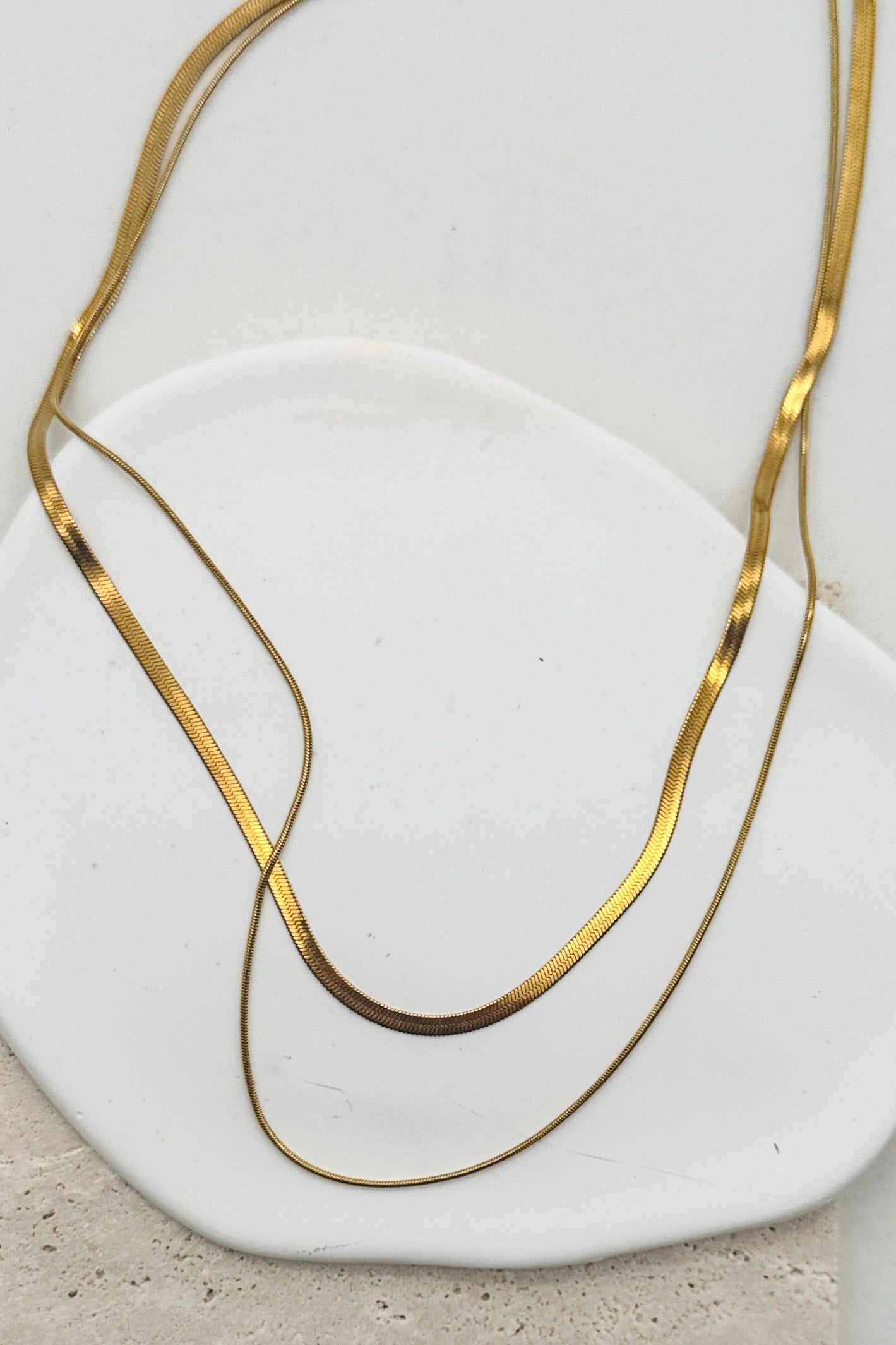 Gold necklace on a white stone surface