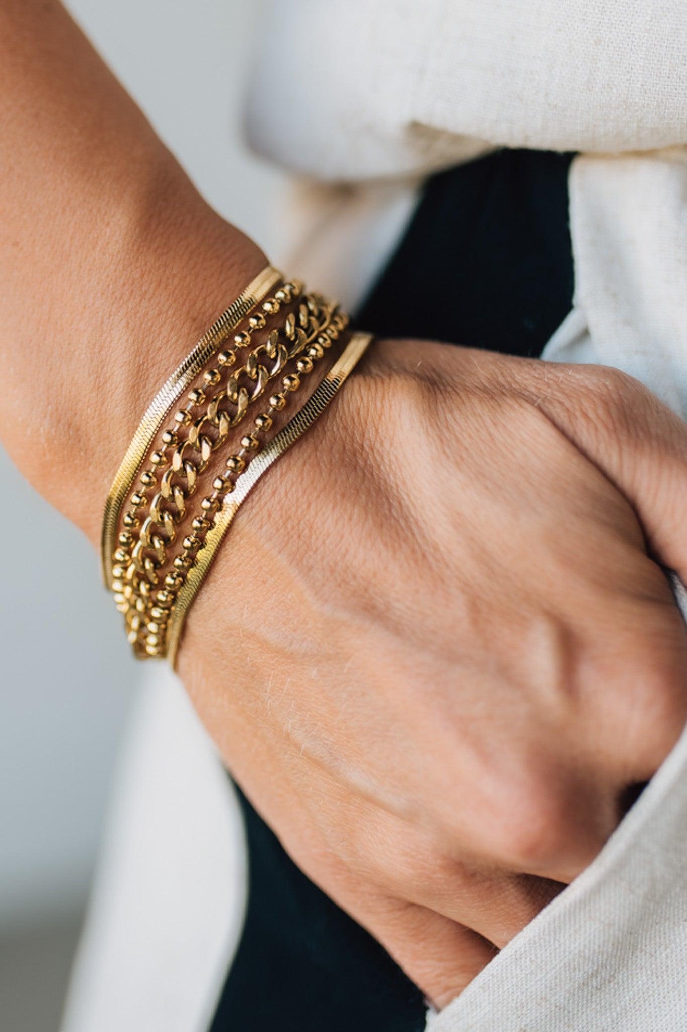 Close-up of a wrist wearing gold chain bracelets with a blurred background