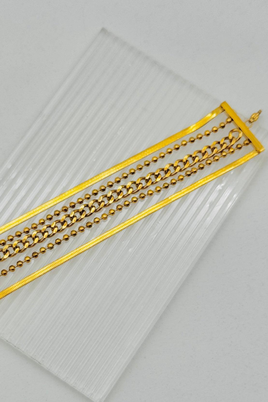 Gold chain belt on a clear plastic sheet with a light gray background
