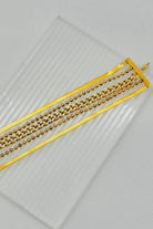 Gold chain belt on a clear plastic sheet with a light gray background