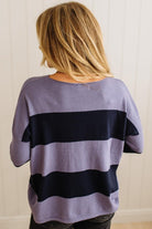 Person wearing a purple and navy striped sweater against a plain background