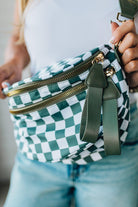 Blonde woman in a white tank wearing a green and white oversized checkered crossbody bag.