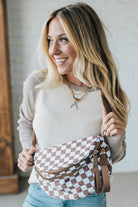 Woman holding a checkered bag in a neutral indoor setting