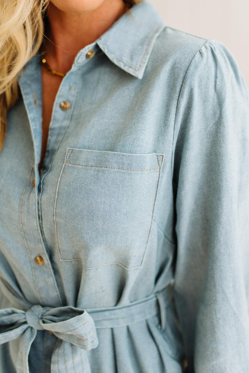 Light blue denim dress with a tie waist on a neutral background
