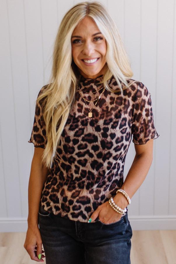Woman wearing a leopard print top with a white wall background