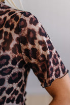 Close-up of a leopard print sleeve on a garment against a neutral background