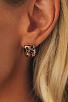 Close-up of an ear wearing a leopard print stud earring.