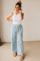 BLONDE WOMAN WEARING WASHED LEOPARD PATTERN PANTS WQITH CURVED SIDE SEAM AND WITH DRAWSTRING WAIST.