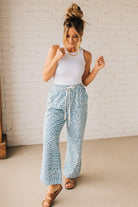 BLONDE WOMAN WEARING WASHED LEOPARD PATTERN PANTS WQITH CURVED SIDE SEAM AND WITH DRAWSTRING WAIST.