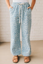 BLONDE WOMAN WEARING WASHED LEOPARD PATTERN PANTS WQITH CURVED SIDE SEAM AND WITH DRAWSTRING WAIST.