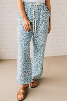 BLONDE WOMAN WEARING WASHED LEOPARD PATTERN PANTS WQITH CURVED SIDE SEAM AND WITH DRAWSTRING WAIST.