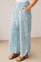 BLONDE WOMAN WEARING WASHED LEOPARD PATTERN PANTS WQITH CURVED SIDE SEAM AND WITH DRAWSTRING WAIST.