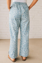 BLONDE WOMAN WEARING WASHED LEOPARD PATTERN PANTS WQITH CURVED SIDE SEAM AND WITH DRAWSTRING WAIST.