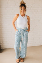 BLONDE WOMAN WEARING WASHED LEOPARD PATTERN PANTS WQITH CURVED SIDE SEAM AND WITH DRAWSTRING WAIST.