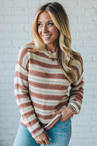 Woman wearing a striped sweater in front of a white brick wall