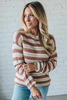 Woman wearing a striped sweater in front of a white brick wall